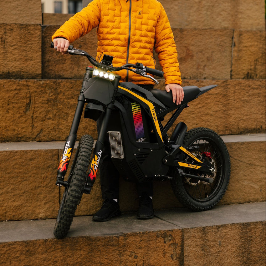 Freego Nova 4 electric dirt bike held by a rider in an orange jacket on stone steps