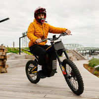 Freego Nova 4 electric dirt bike rider on a boardwalk by a bridge