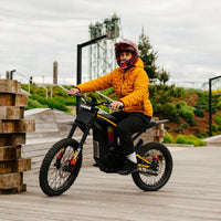Freego Nova 4 electric dirt bike rider seated on a wooden boardwalk