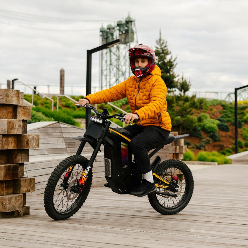 Freego Nova 4 electric dirt bike rider seated on a wooden boardwalk