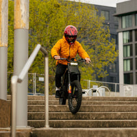 Freego Nova 4 electric dirt bike rider descending outdoor steps