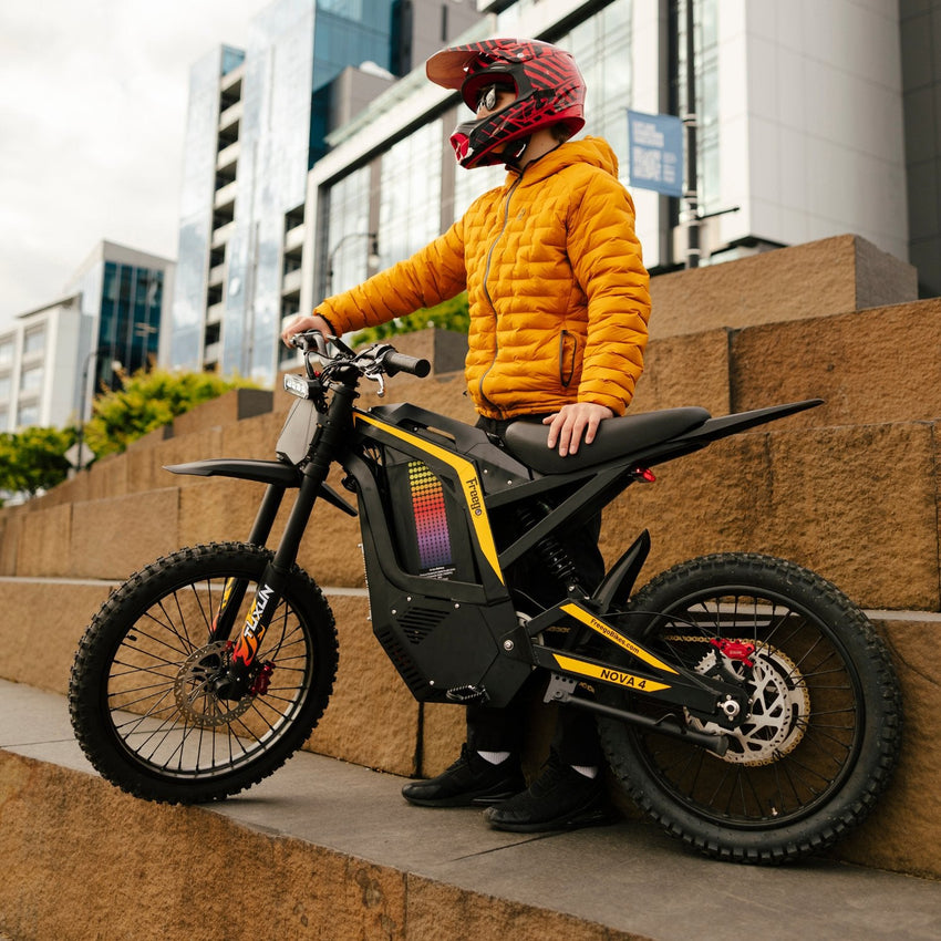 Freego Nova 4 electric dirt bike with rider standing beside it on a city plaza