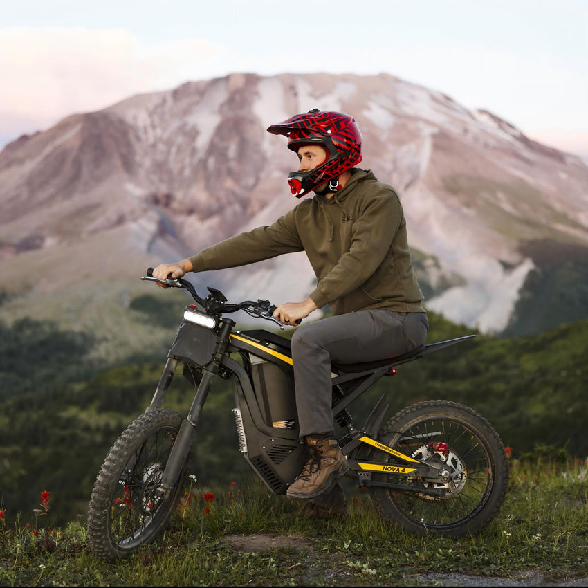 Freego Nova 4 electric dirt bike rider seated on a trail with mountain behind