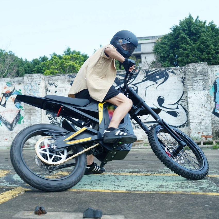 Freego Nova 4 electric dirt bike rider leaning into a turn by a graffiti wall