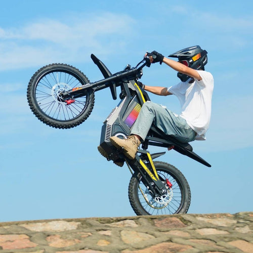 Freego Nova 4 electric dirt bike rider doing a wheelie against blue sky